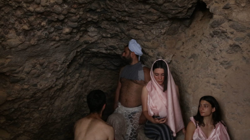 Two young men and two young women are in a cave wearing costumes.The cave is the site of Lot’s cave near Gwar Al Safi in Jordan.