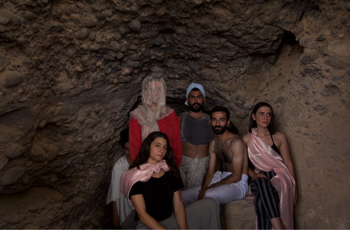 Two young men and three young women are in a cave wearing costumes and posing for the camera.The cave is the site of Lot’s cave near Gwar Al Safi in Jordan.
