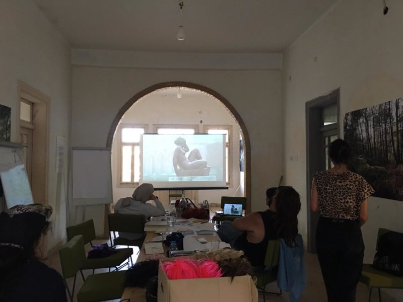 Five women look at a screen with a video projector, projecting a film by Marguerite Duras.